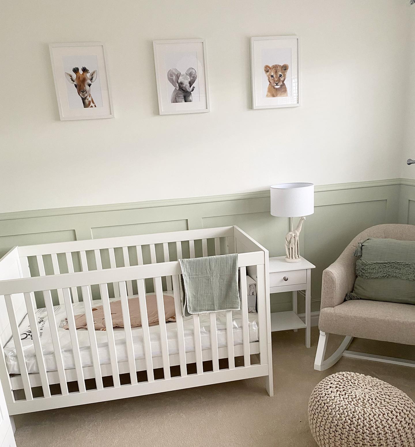 A sage green nursery with a white crib and animal pictures.