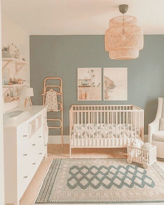A sage green nursery with white furniture.