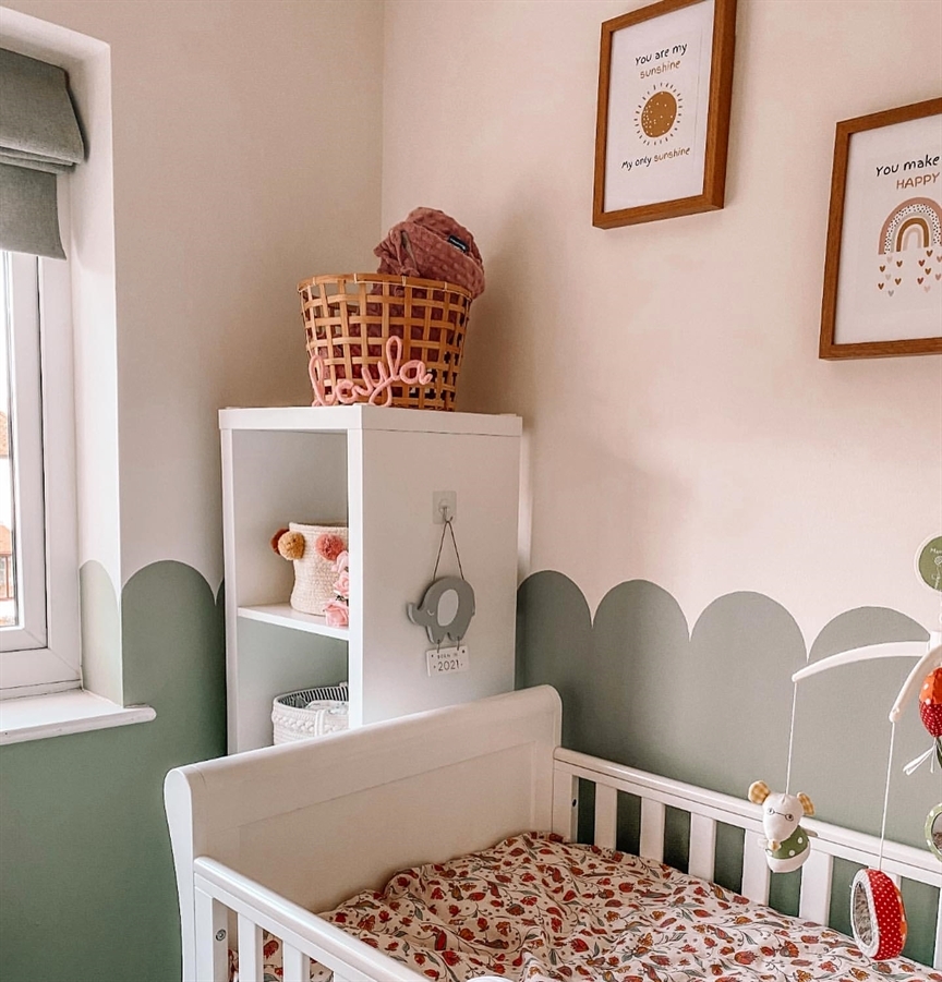 A sage green nursery with a white crib.