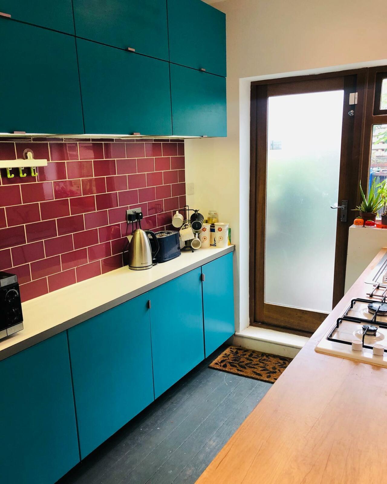 A kitchen with turquoise tiled walls.
