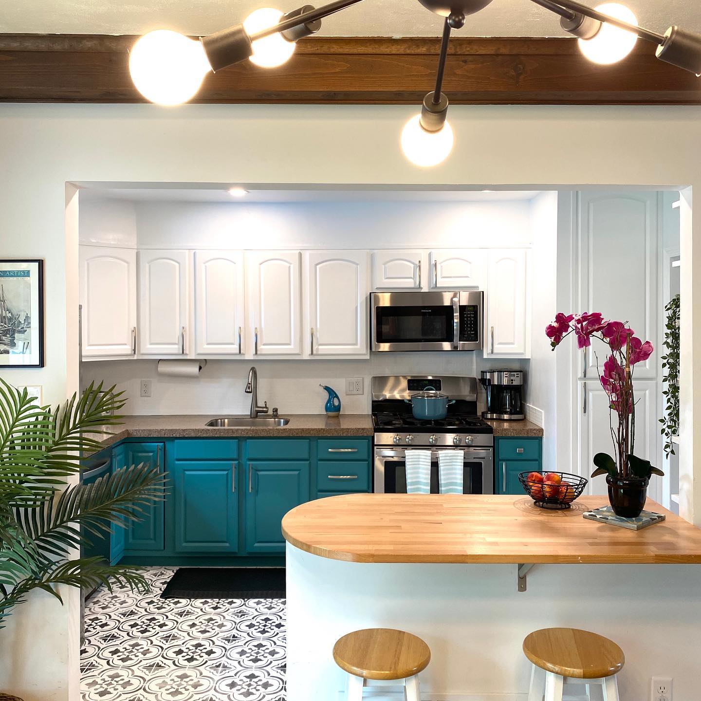 A kitchen with turquoise cabinets and stools.