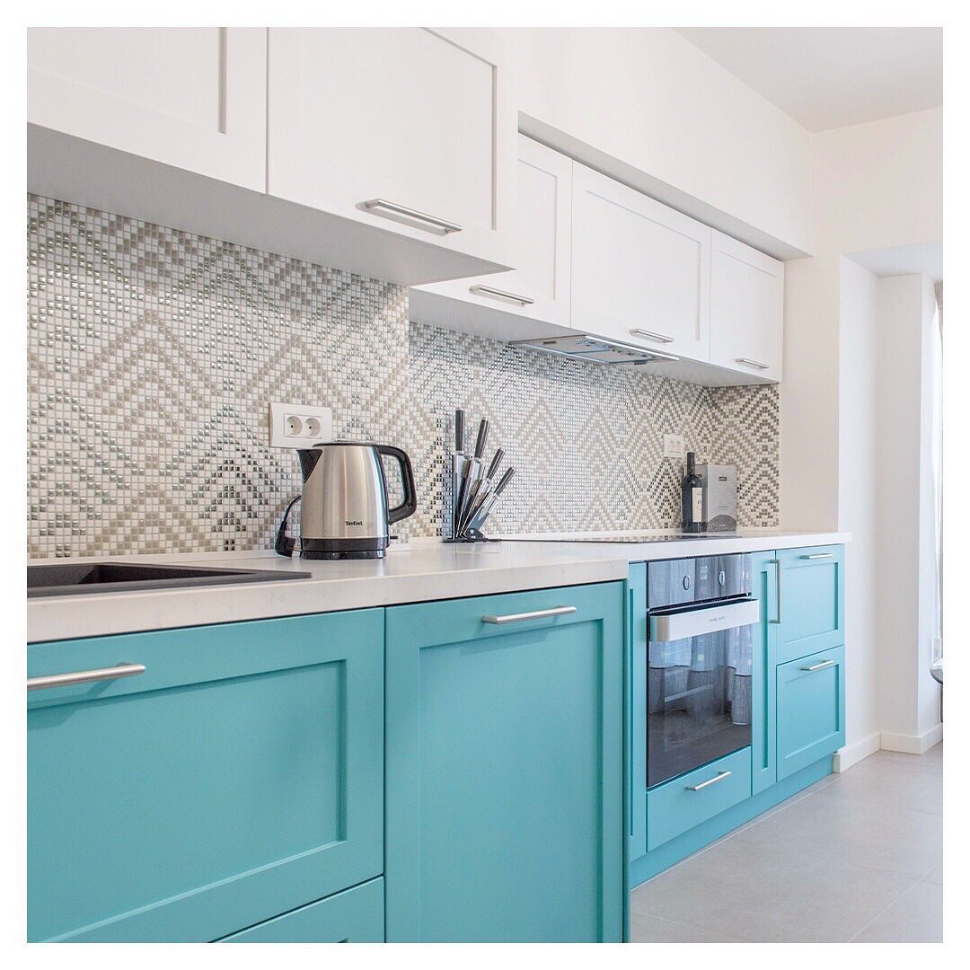 A kitchen with turquoise cabinets and white counter tops.