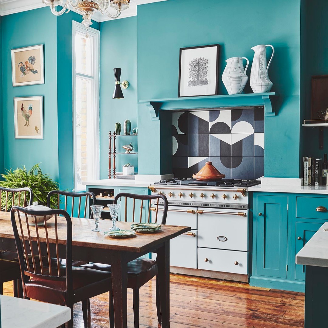 A kitchen with teal walls and turquoise kitchen cabinets.