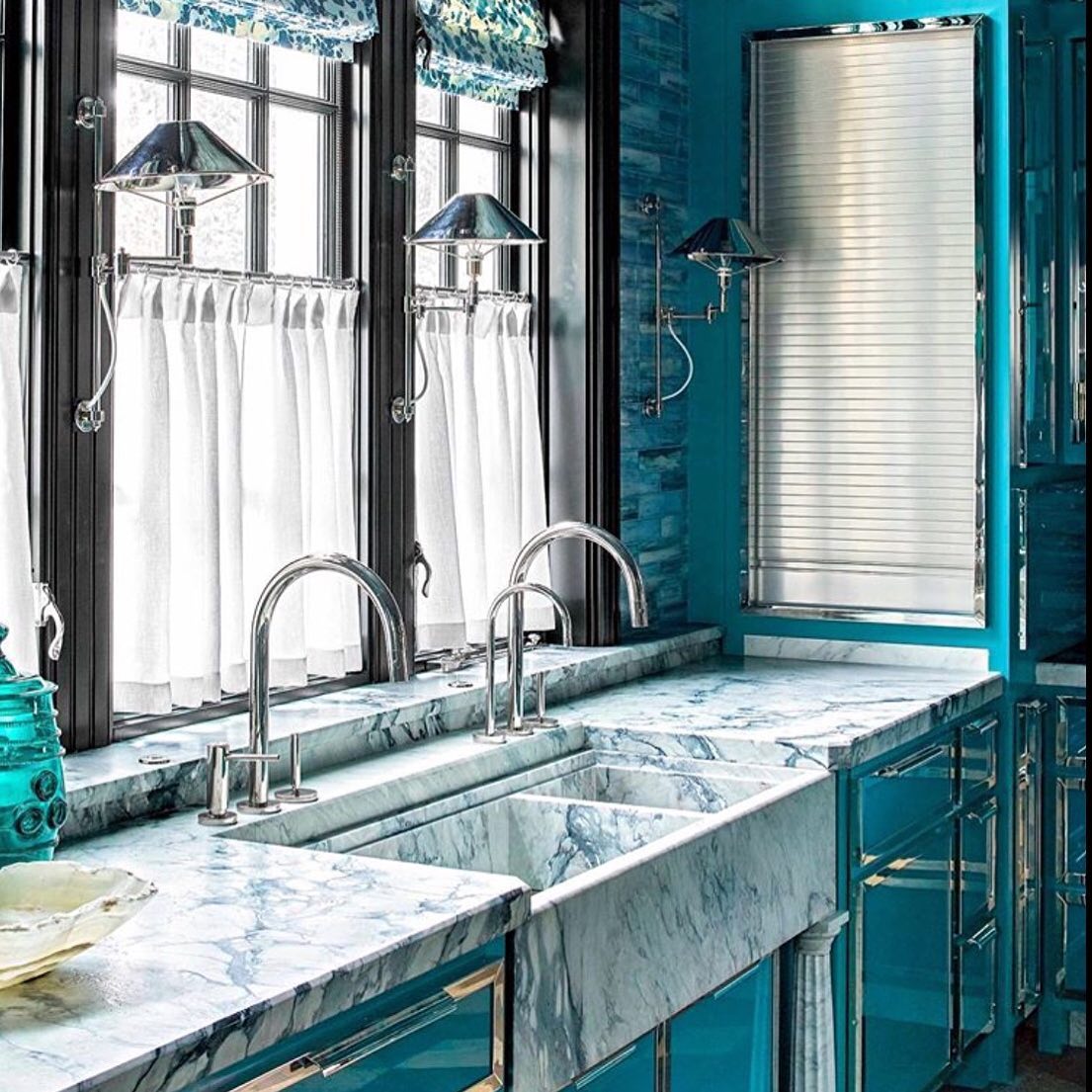 A turquoise kitchen with marble counter tops.