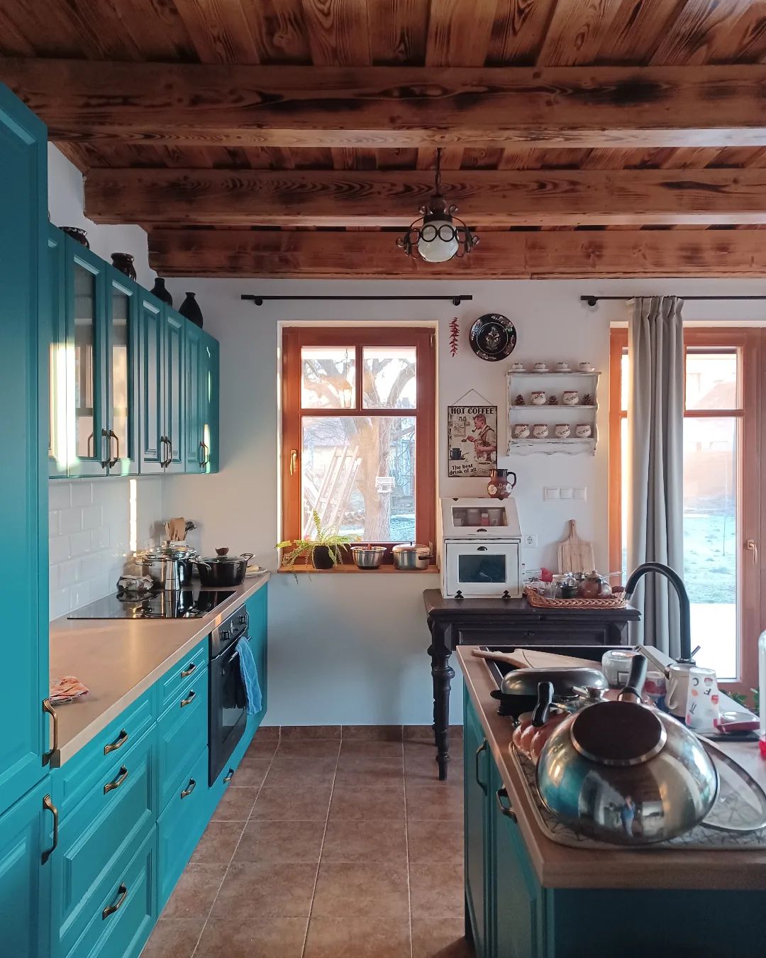 A kitchen with turquoise cabinets and wooden beams.