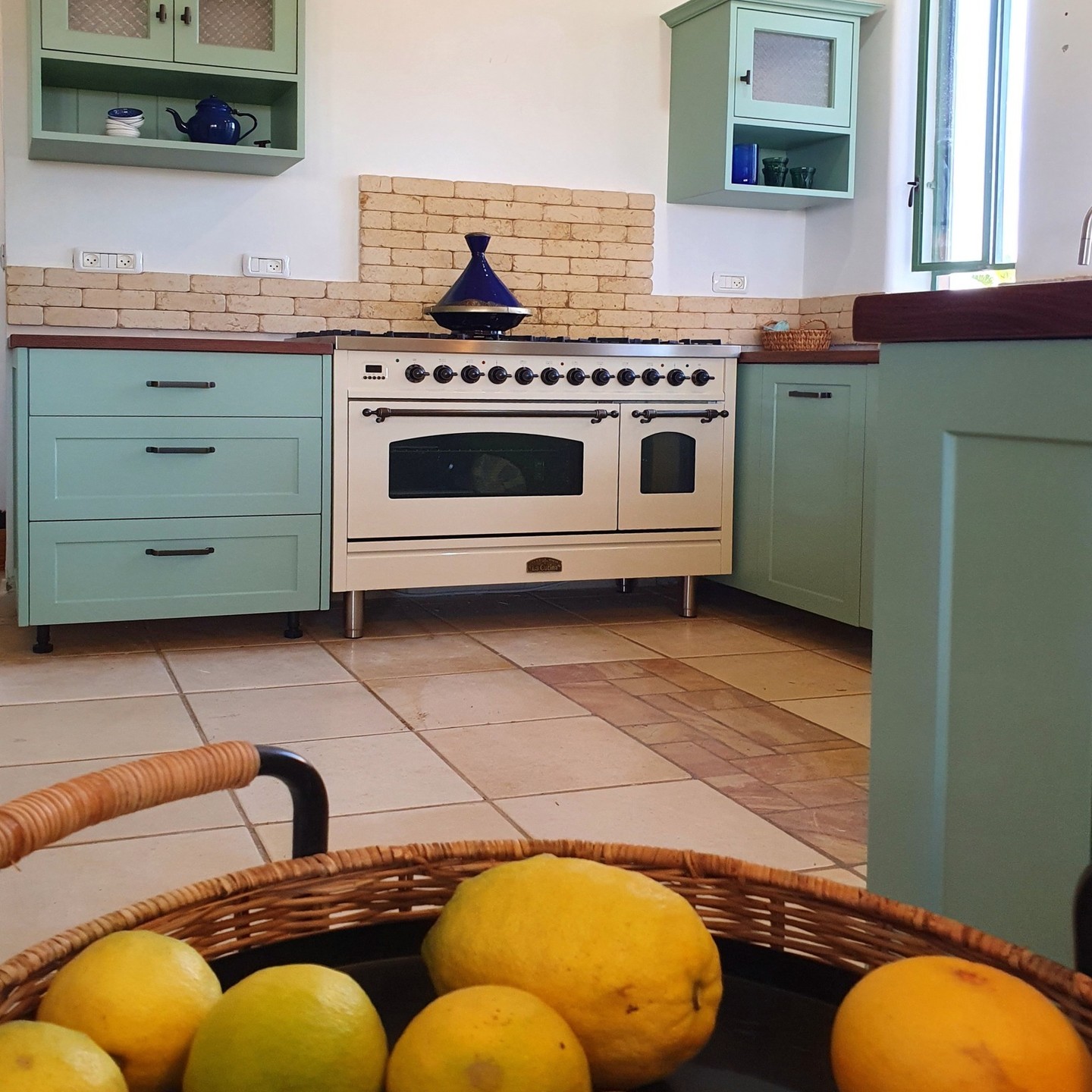 A basket of lemons decorates the turquoise kitchen cabinets.