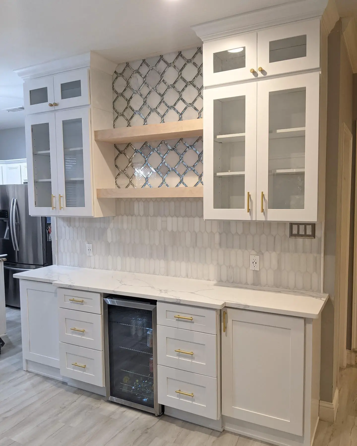A kitchen with white cabinets and a refrigerator.