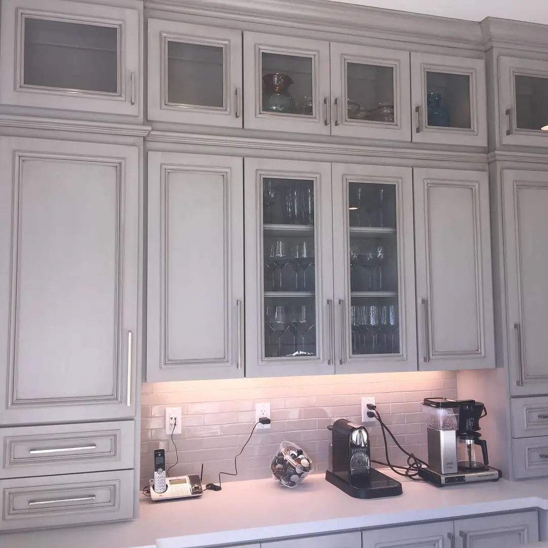 A kitchen with gray cabinets and a coffee maker.