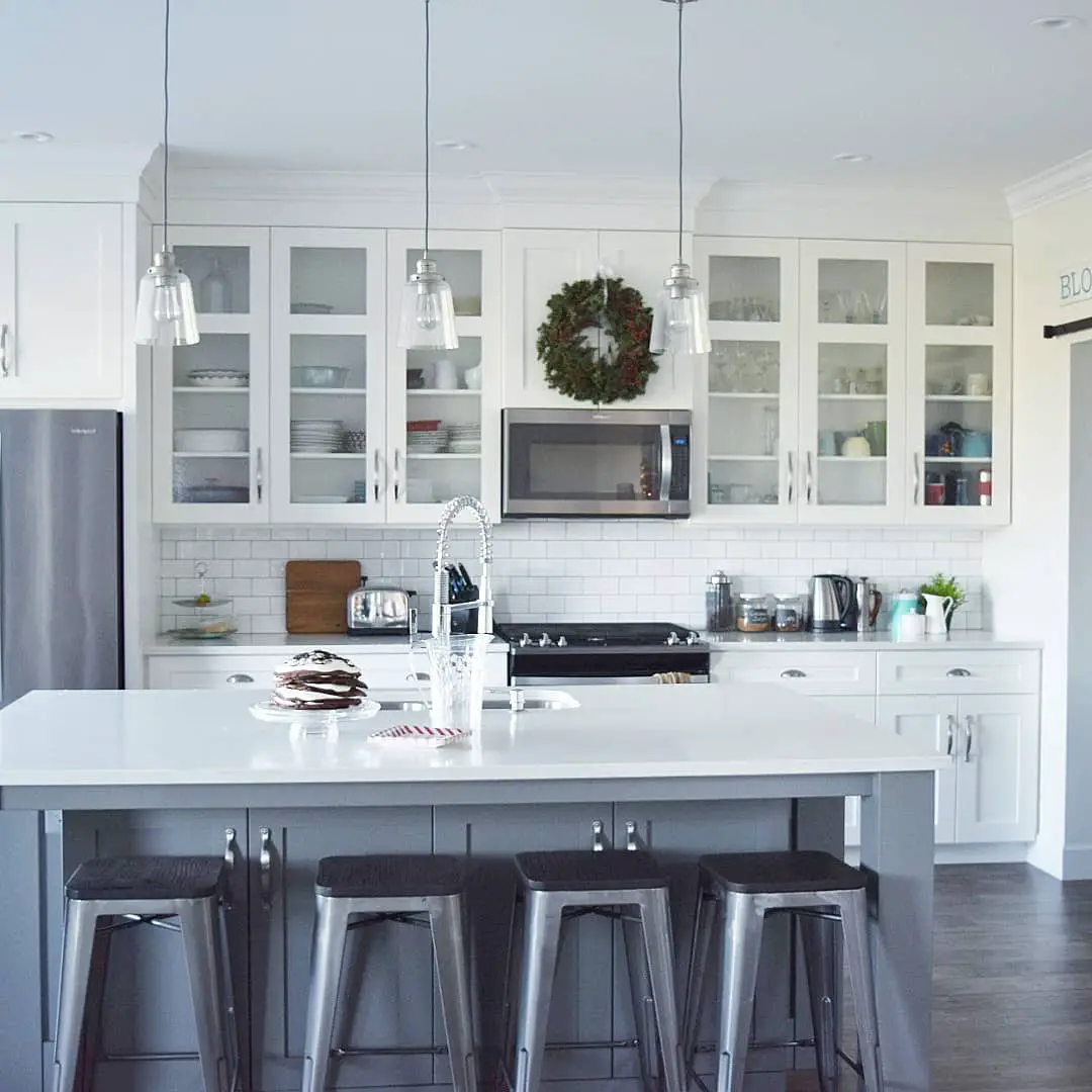 A kitchen with white cabinets and stools.
