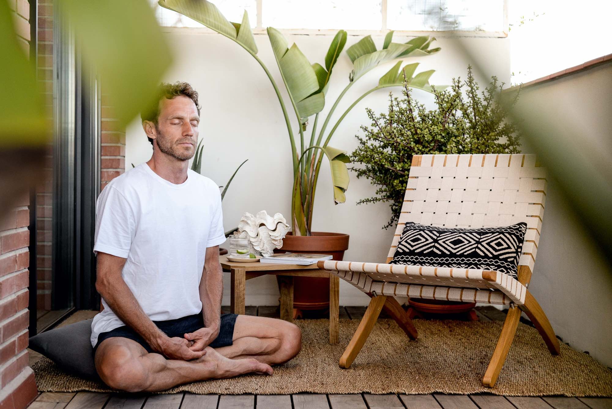A man fostering the connection between home design and mental well-being by meditating on a deck.