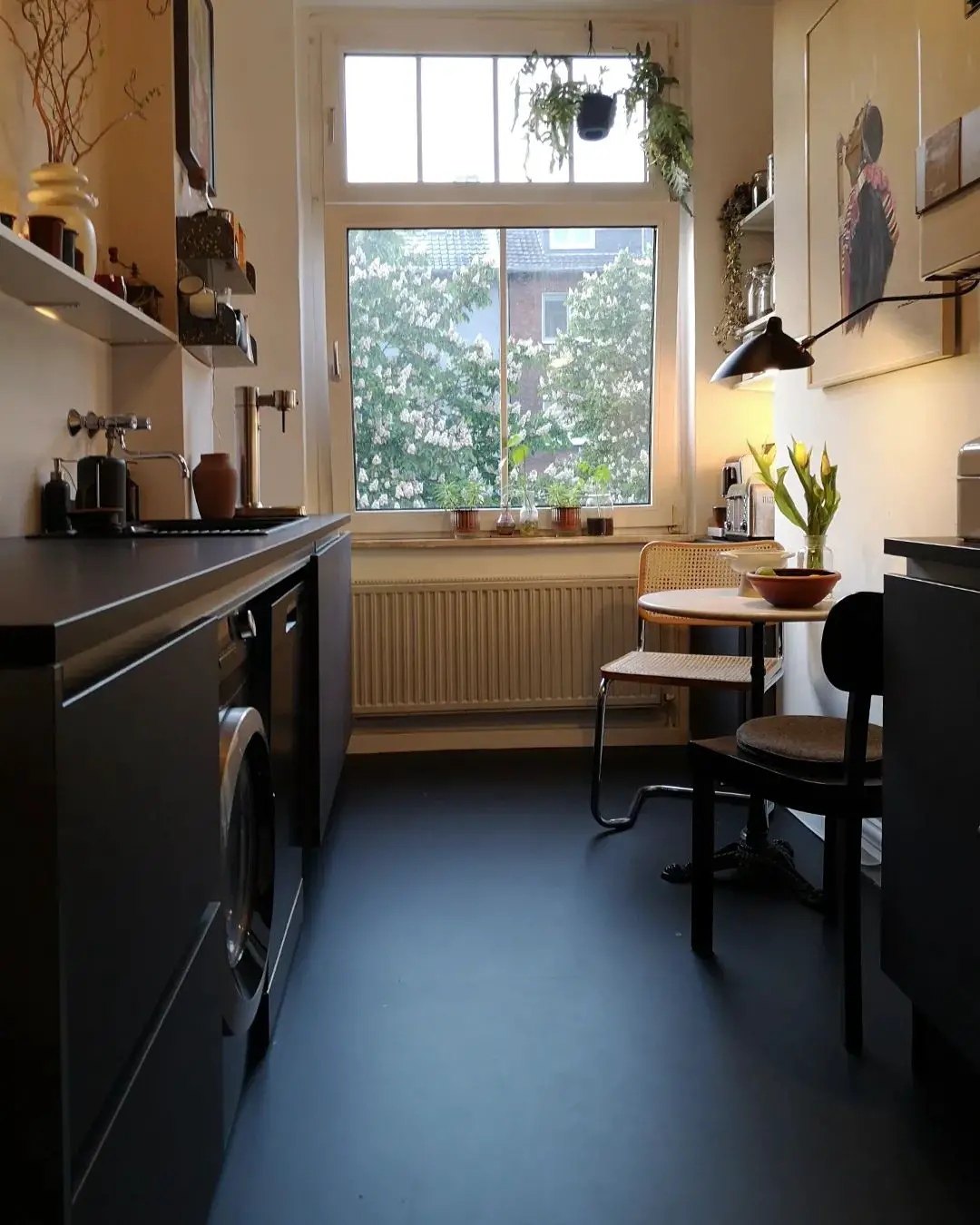 A black kitchen with a table and chairs on a black kitchen floor.