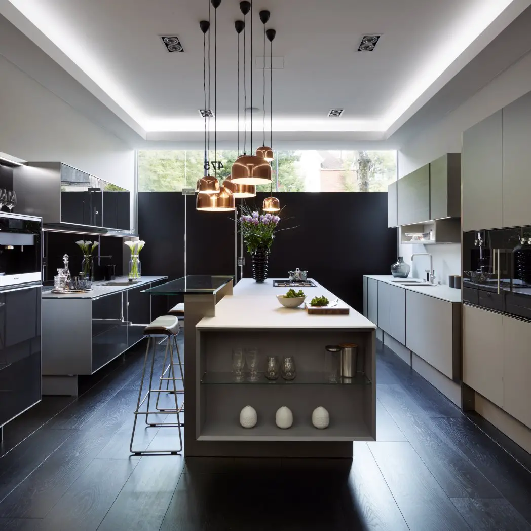 A modern kitchen with a large island and pendant lights, featuring a black kitchen floor.
