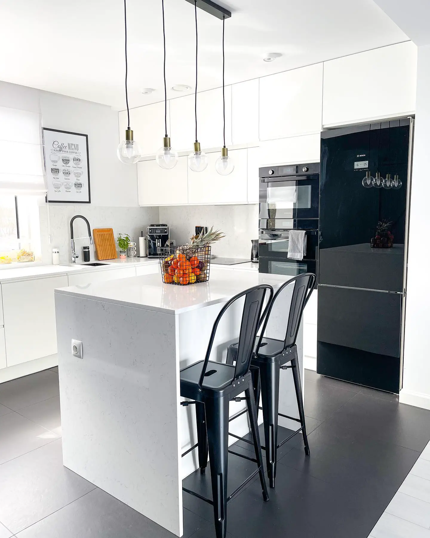 A kitchen with a black island and black stools.