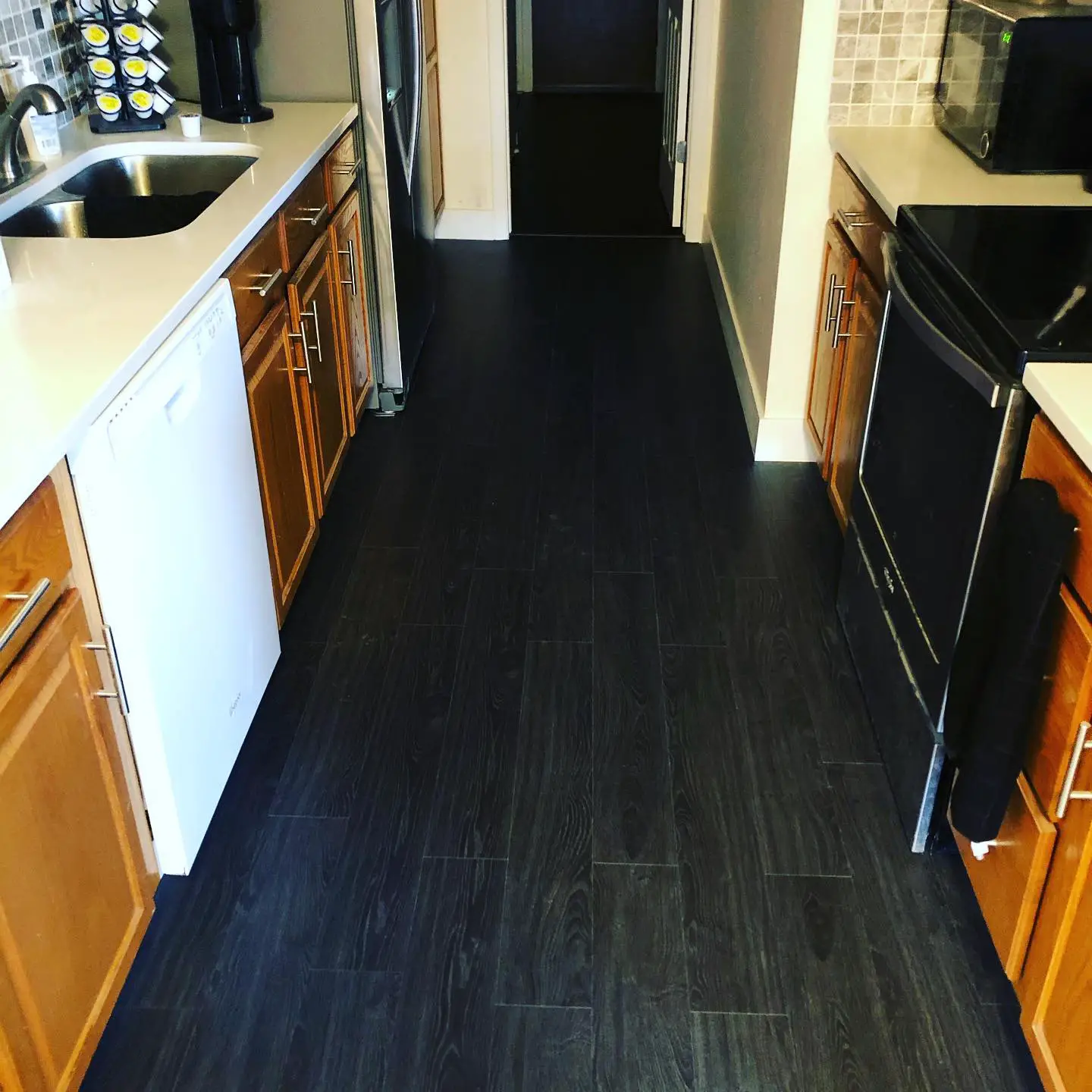 A kitchen with a black floor and wooden cabinets.