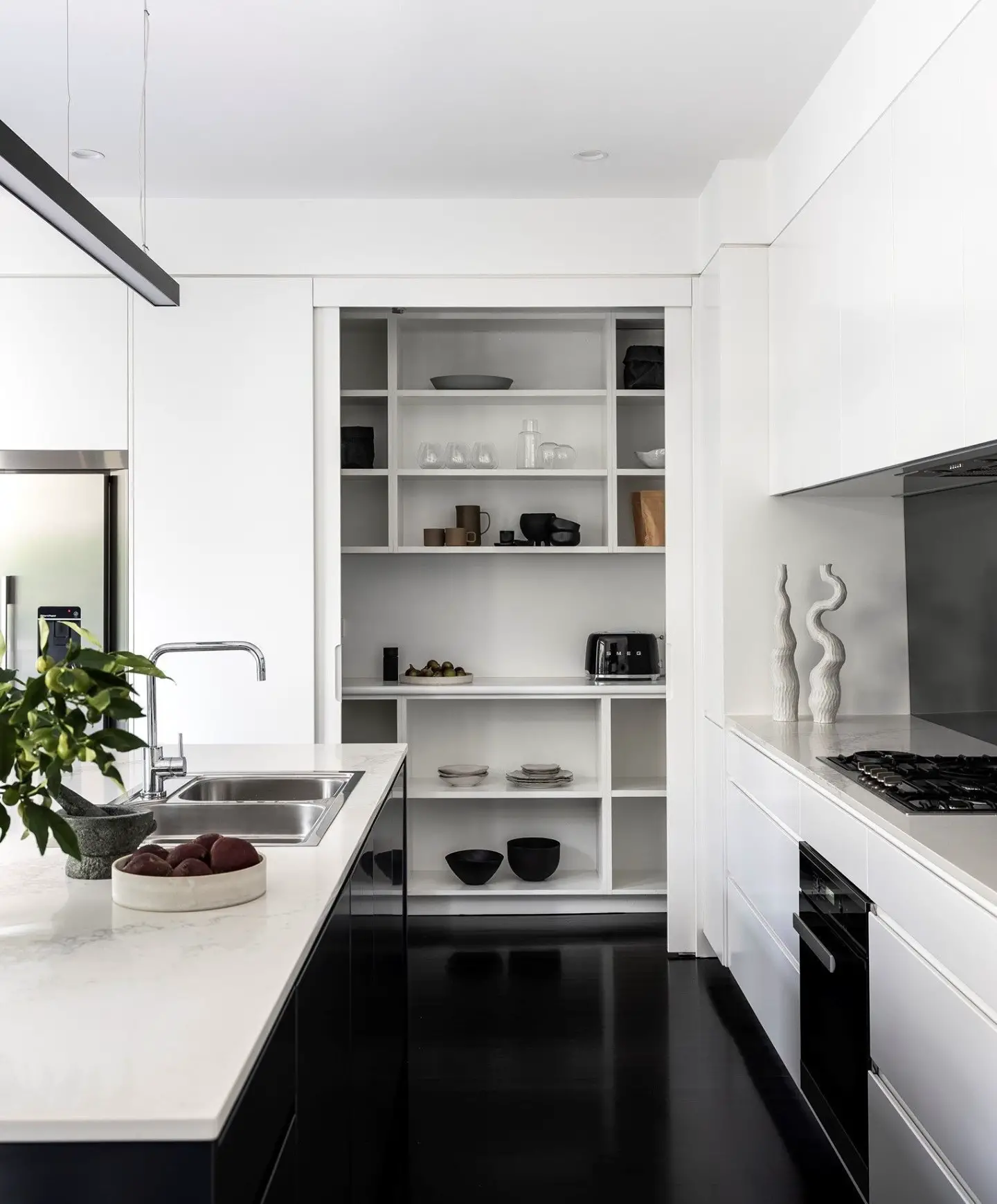 A modern kitchen with white cabinets and black counter tops.