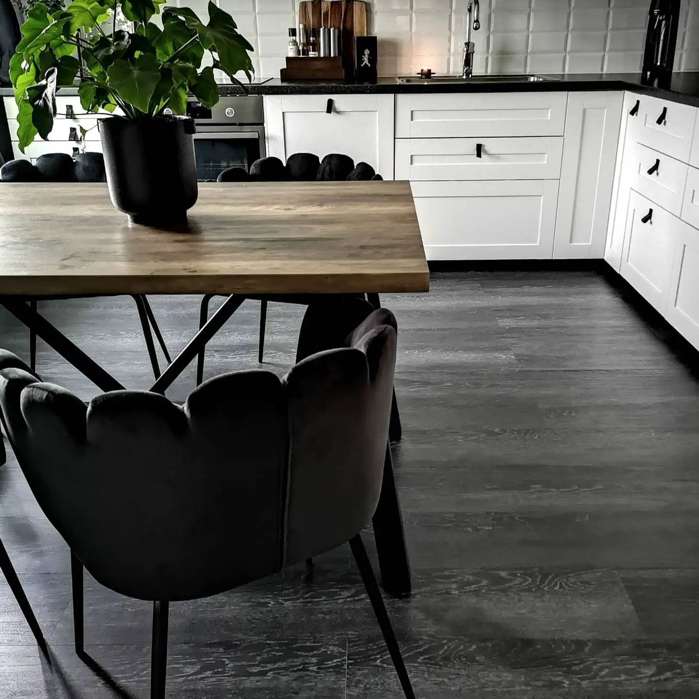 A black and white kitchen with a table and chairs featuring a black kitchen floor.