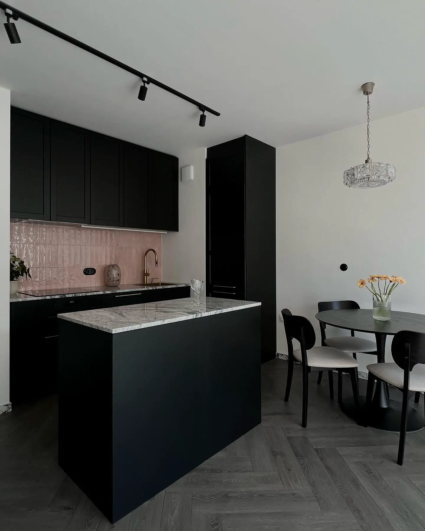 A kitchen with black cabinets and a dining table on a black kitchen floor.