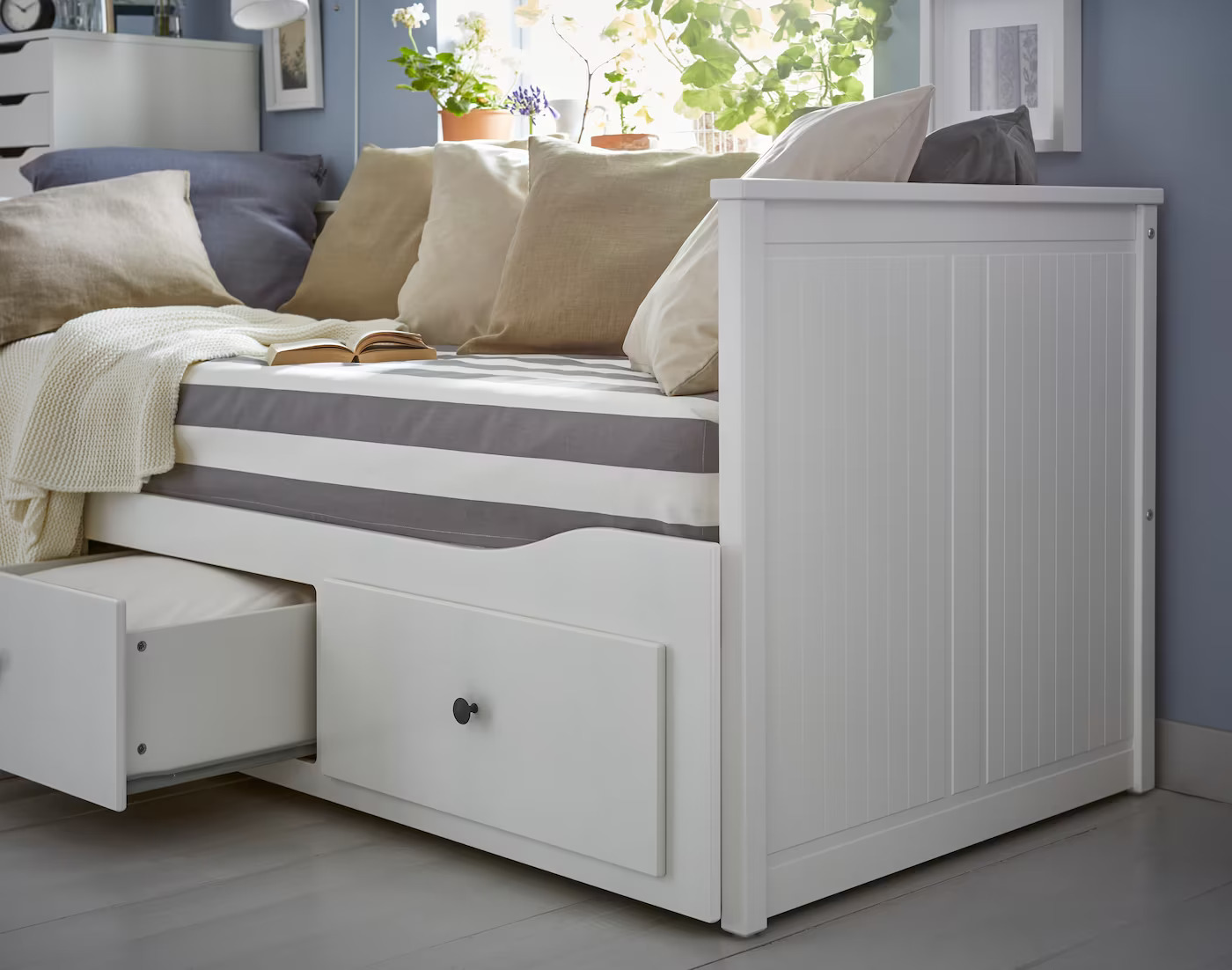 A multifunctional white daybed, featuring drawers for enhanced storage capabilities.
