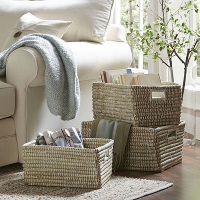 Woven baskets beside sofa with magazines and blanket.