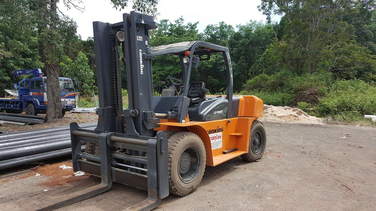 Orange forklift parked at construction site outdoors.