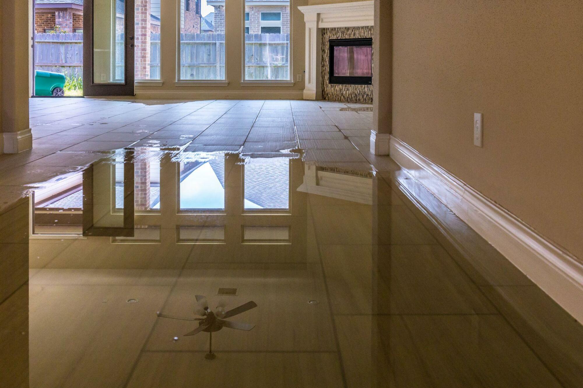 Flooded interior room with reflective water on floor.