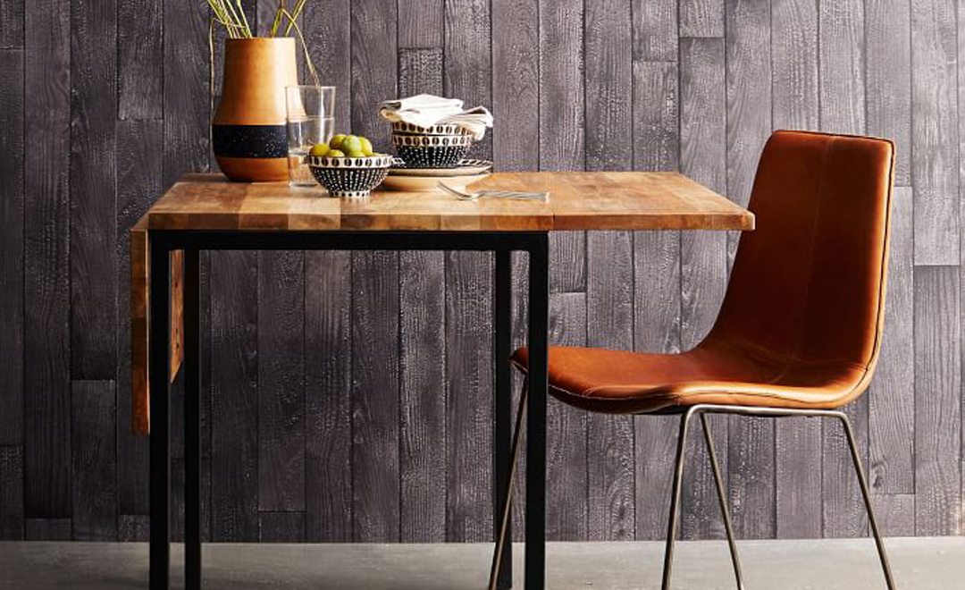 Rustic wooden table with modern chair against textured wall.