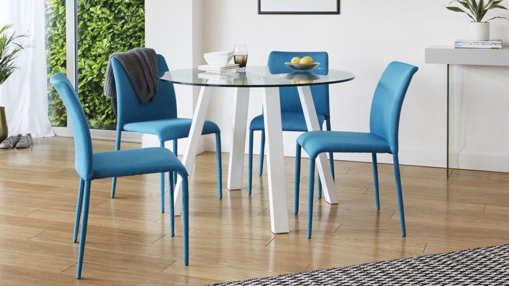 Modern dining room with glass table and blue chairs.