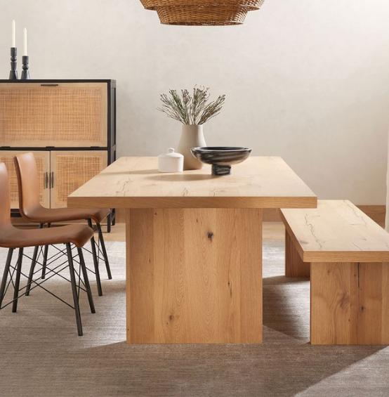 Modern wooden dining table set with bench in bright room.