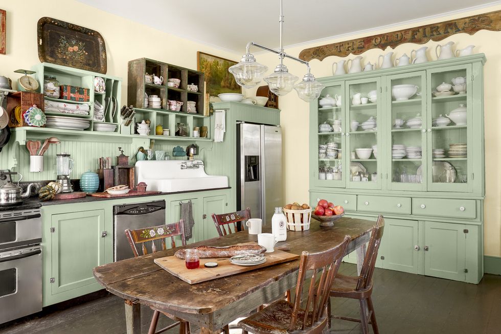 Vintage style kitchen interior with green cabinets and wooden table.
