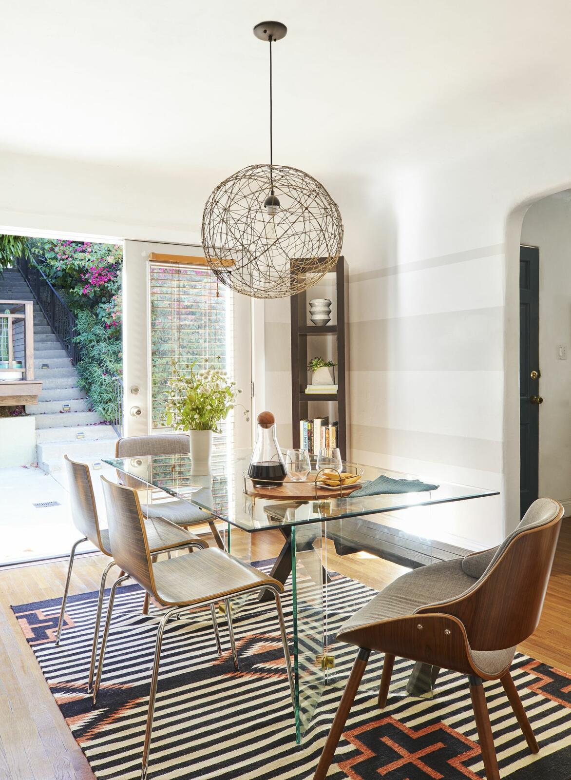 Modern dining room with unique pendant light and striped rug.