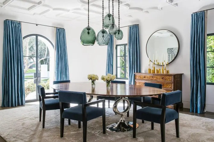 Elegant dining room with blue chairs and pendant lights.