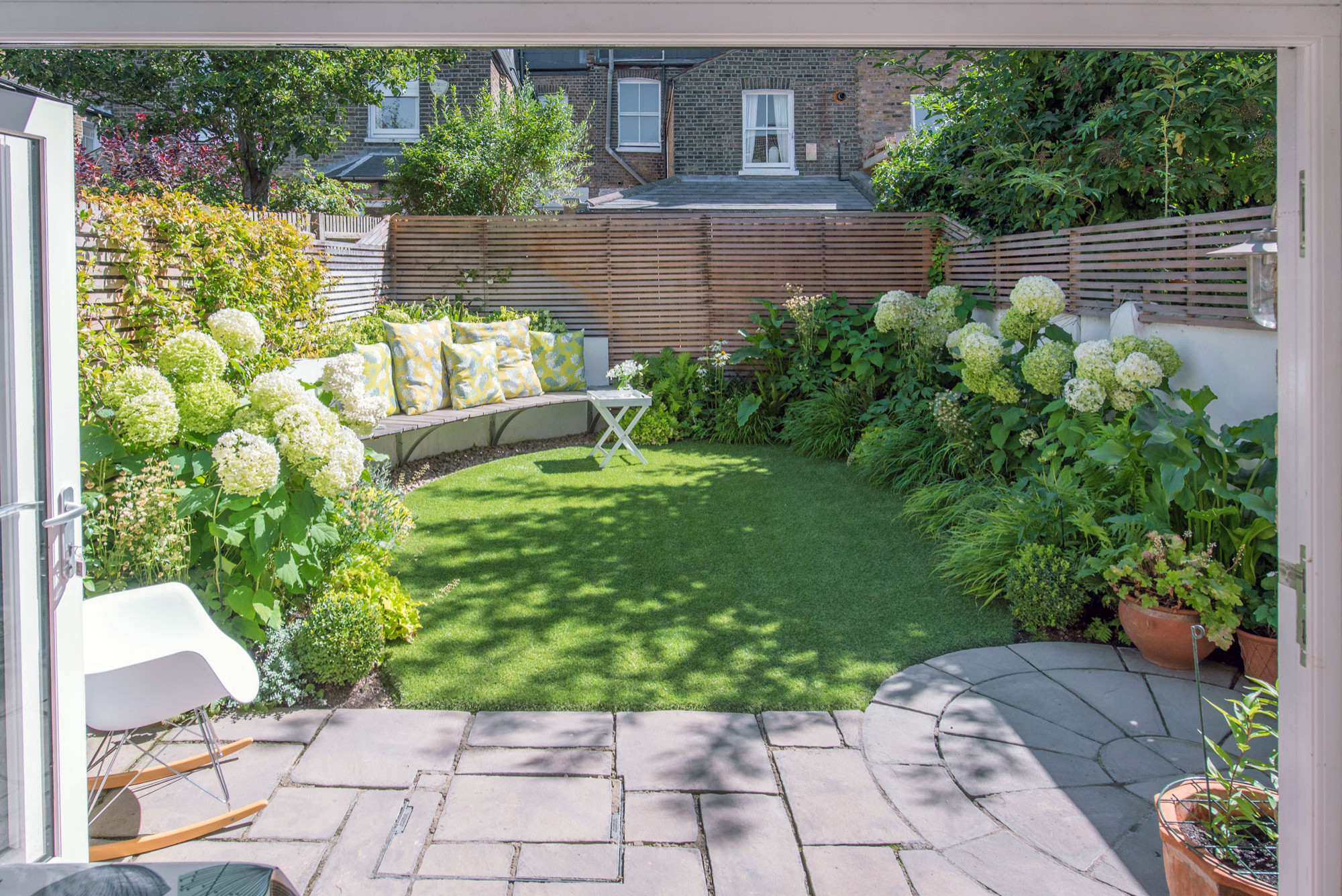 Sunny backyard garden with blooming hydrangeas and patio.