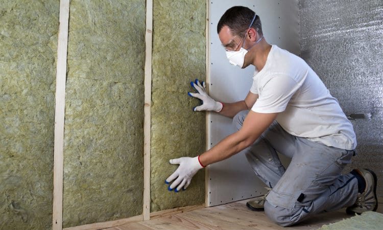 Man installing insulation in wall for thermal efficiency.