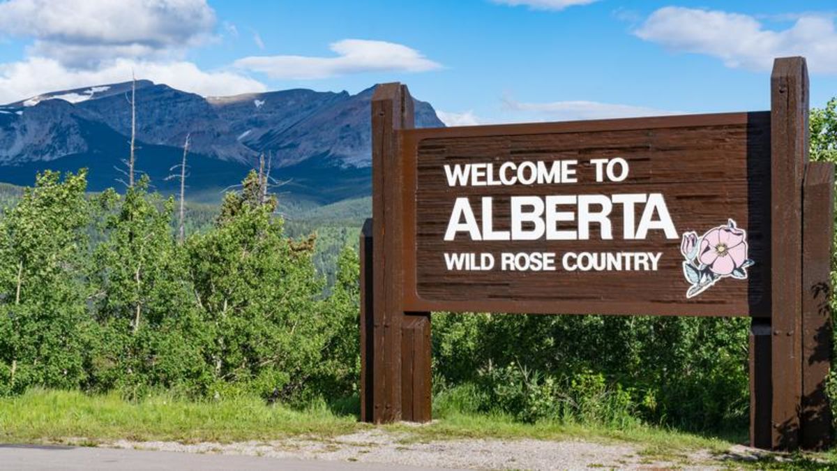 Welcome sign to Alberta, mountains in background.