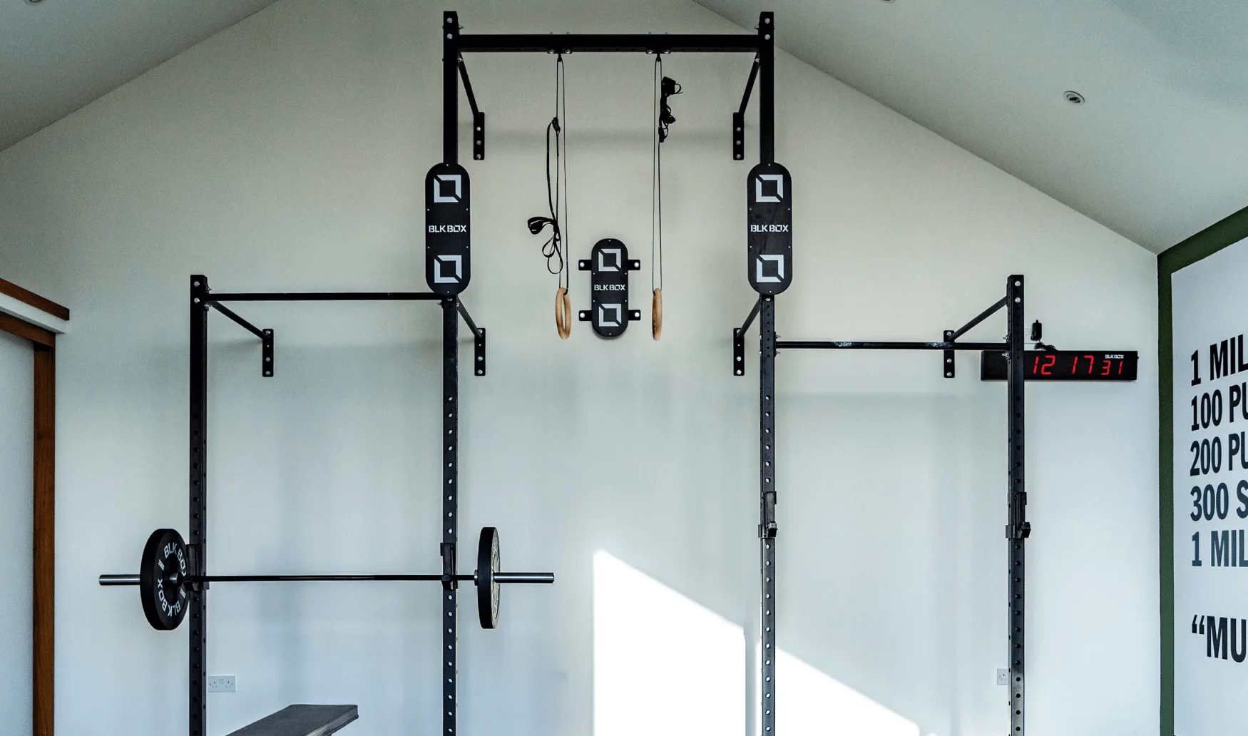 Home gym with squat rack and digital clock.
