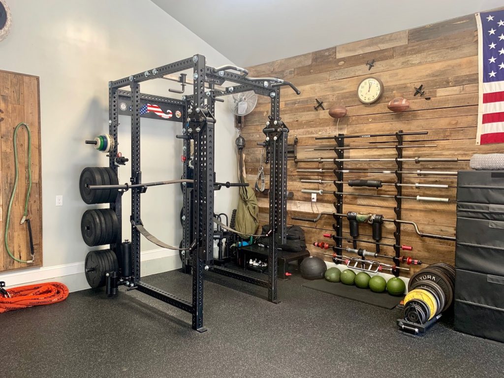 Home gym with squat rack, weights, and American flag.
