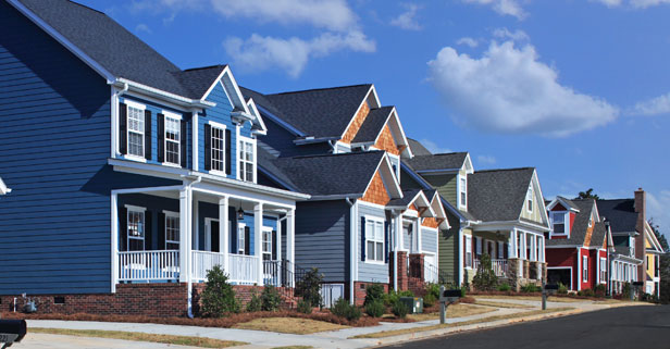 Suburban homes with blue siding and sunny skies.