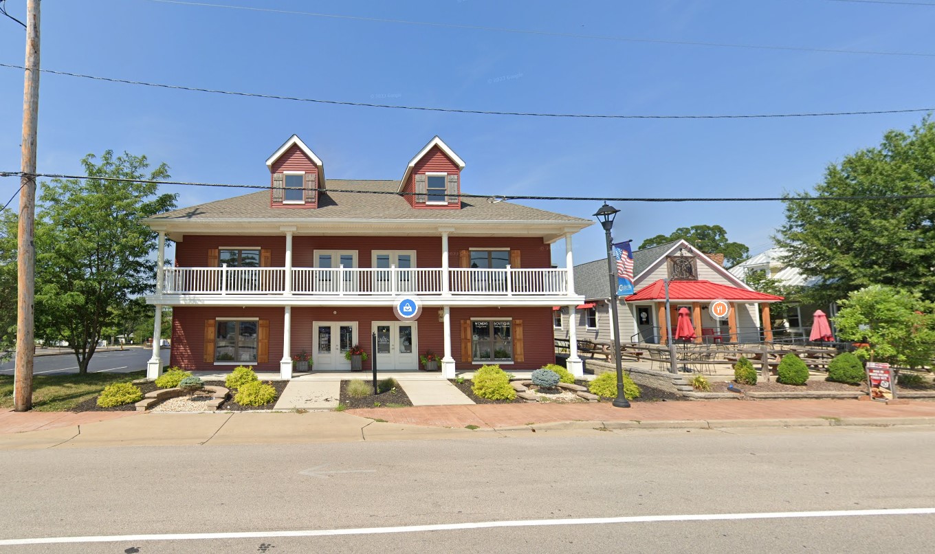 Red two-story building with porch and American flag.