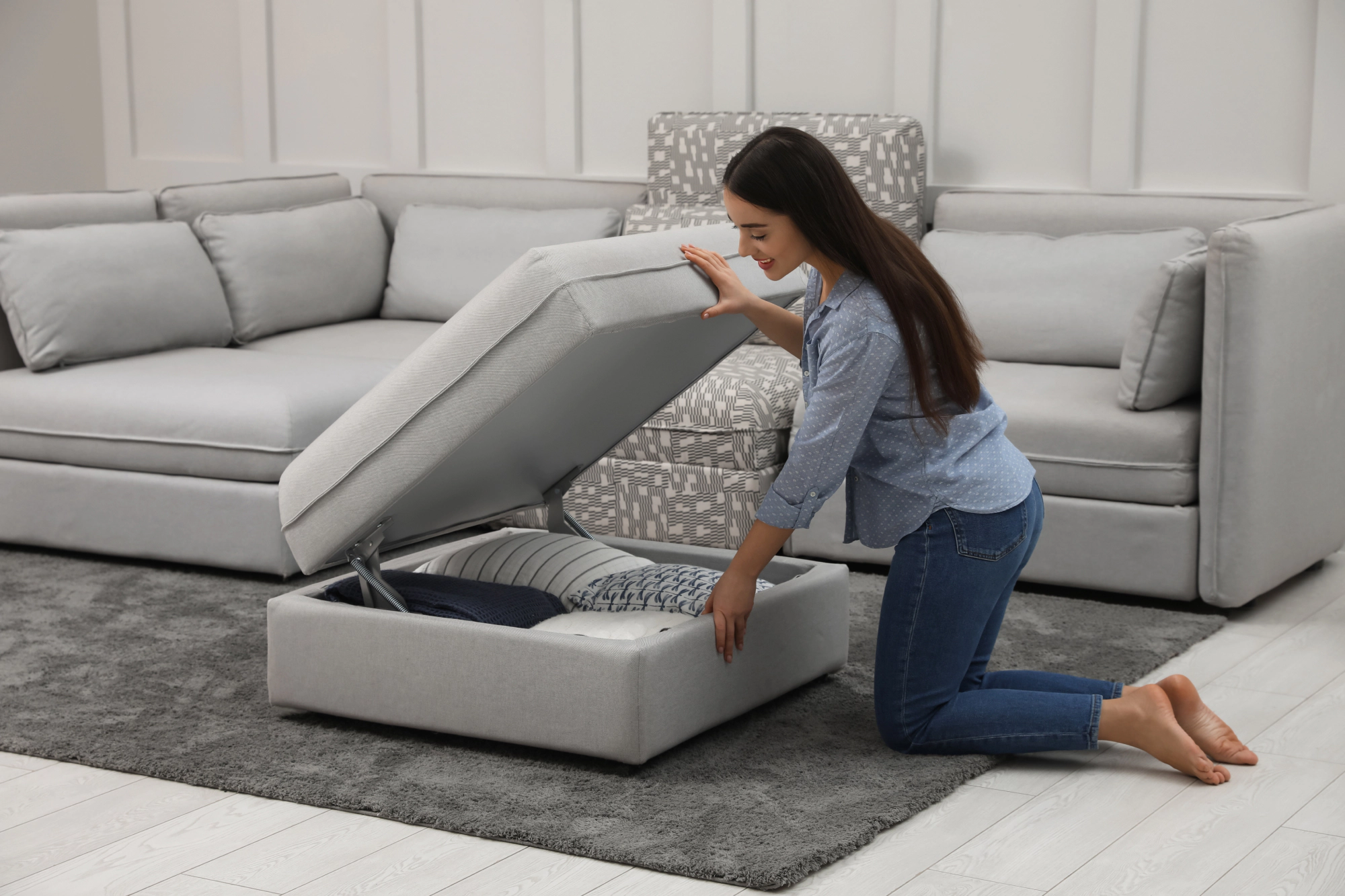 Woman opening storage ottoman in a lounge room.
