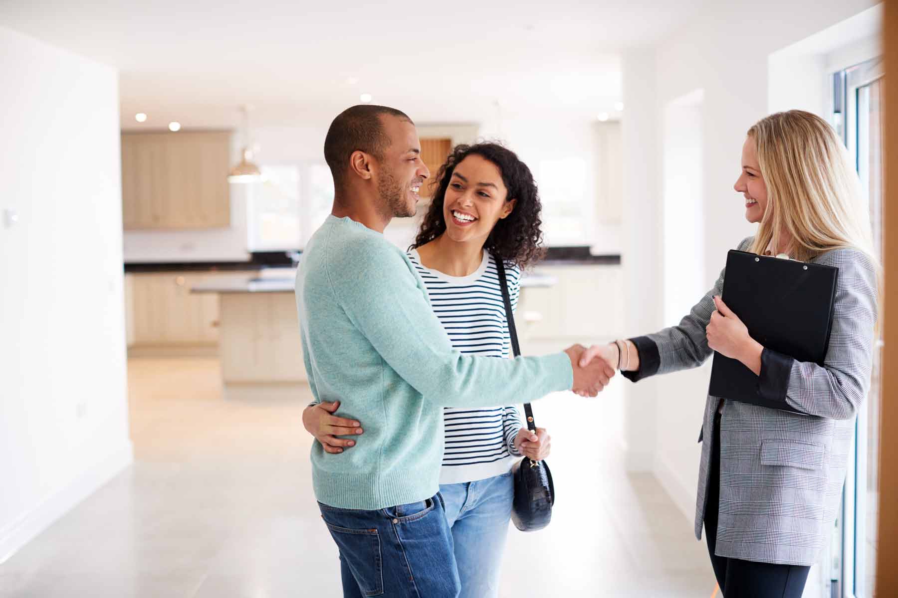 Couple shaking hands with realtor in new home.