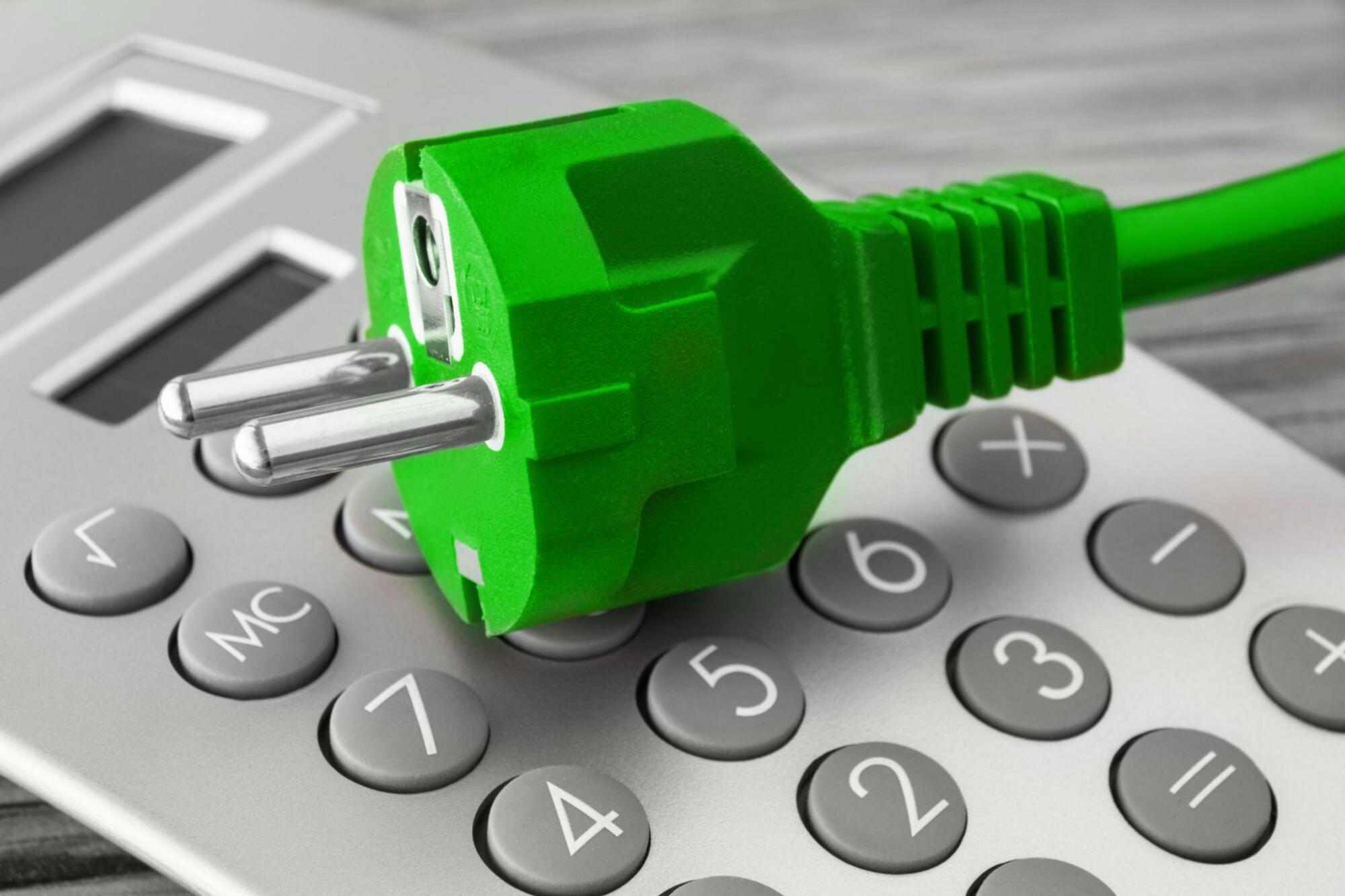Green plug on calculator concept for energy savings.