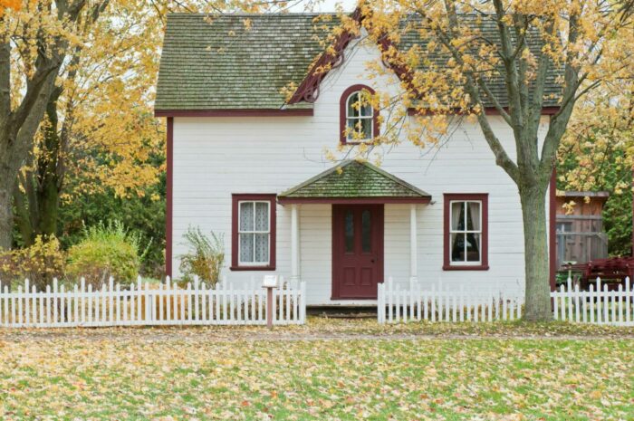 Quaint white house with picket fence in autumn.