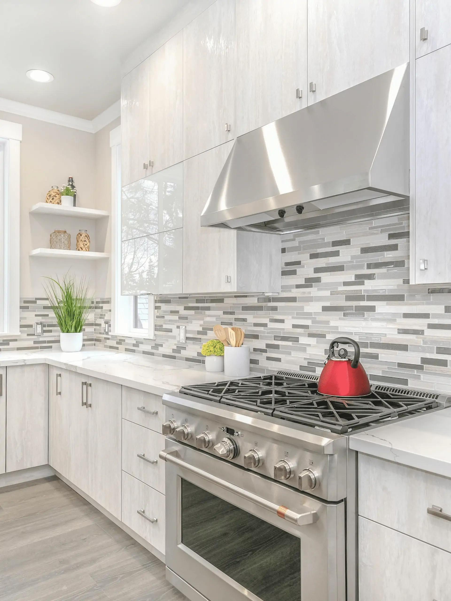 Use color, contrast and pattern to anchor the kitchen, pairing a bold backsplash with neutral cabinets or the reverse