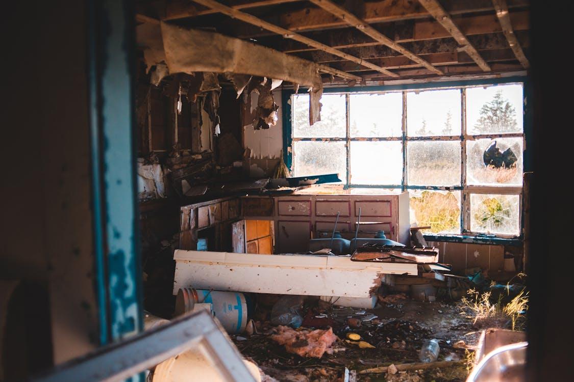 Abandoned kitchen with broken windows and debris