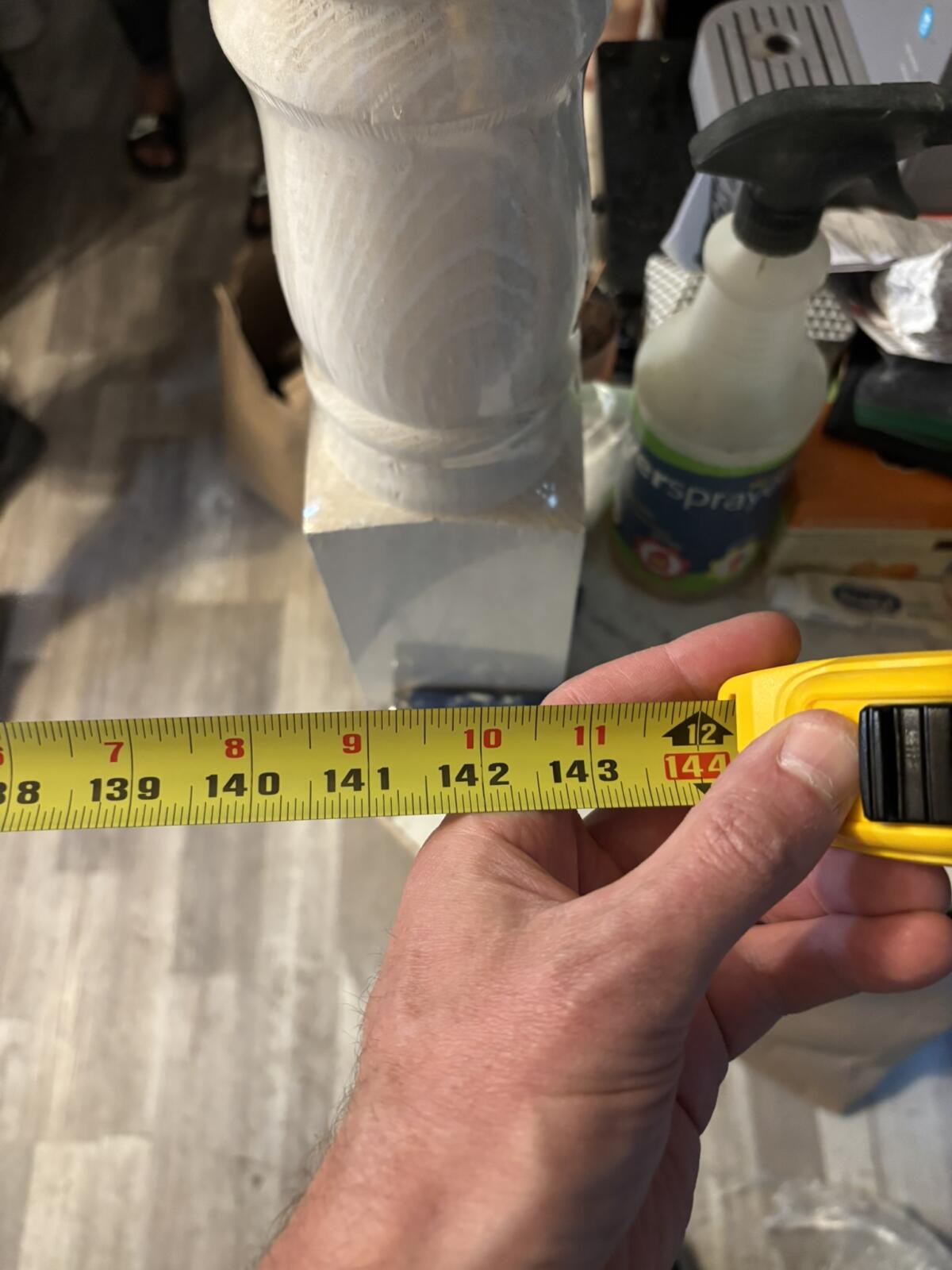 Hand measuring white column with tape measure
