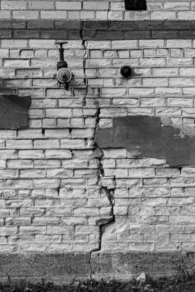 Large vertical crack running through an exterior brick wall, showing possible signs of structural movement.