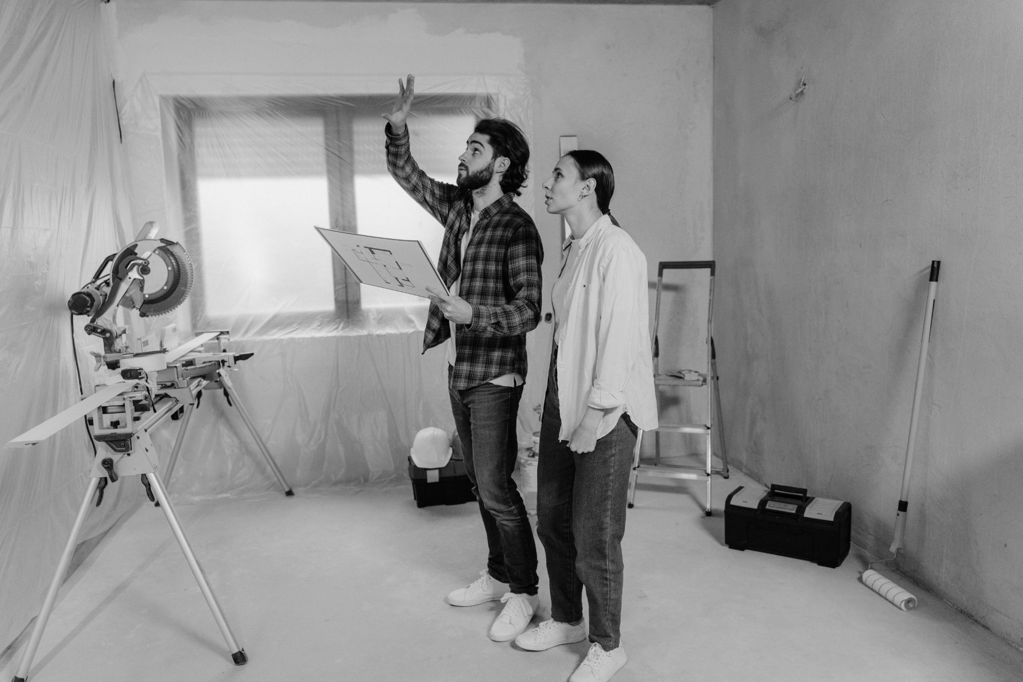 Couple planning renovations in a plastic-covered room