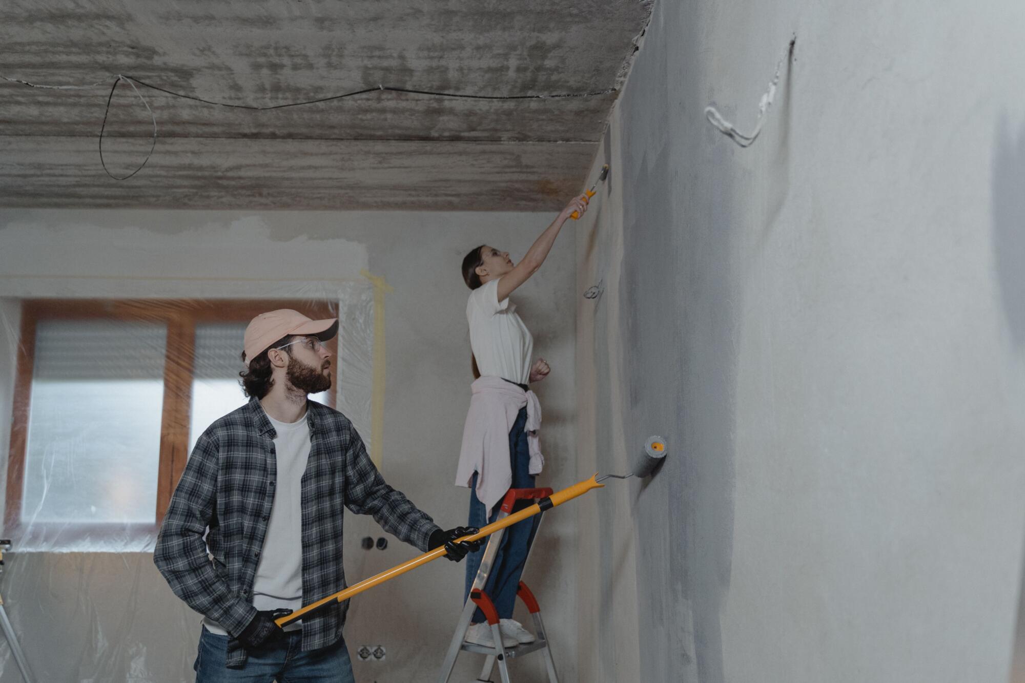Homeowners painting interior walls during a home renovation project.