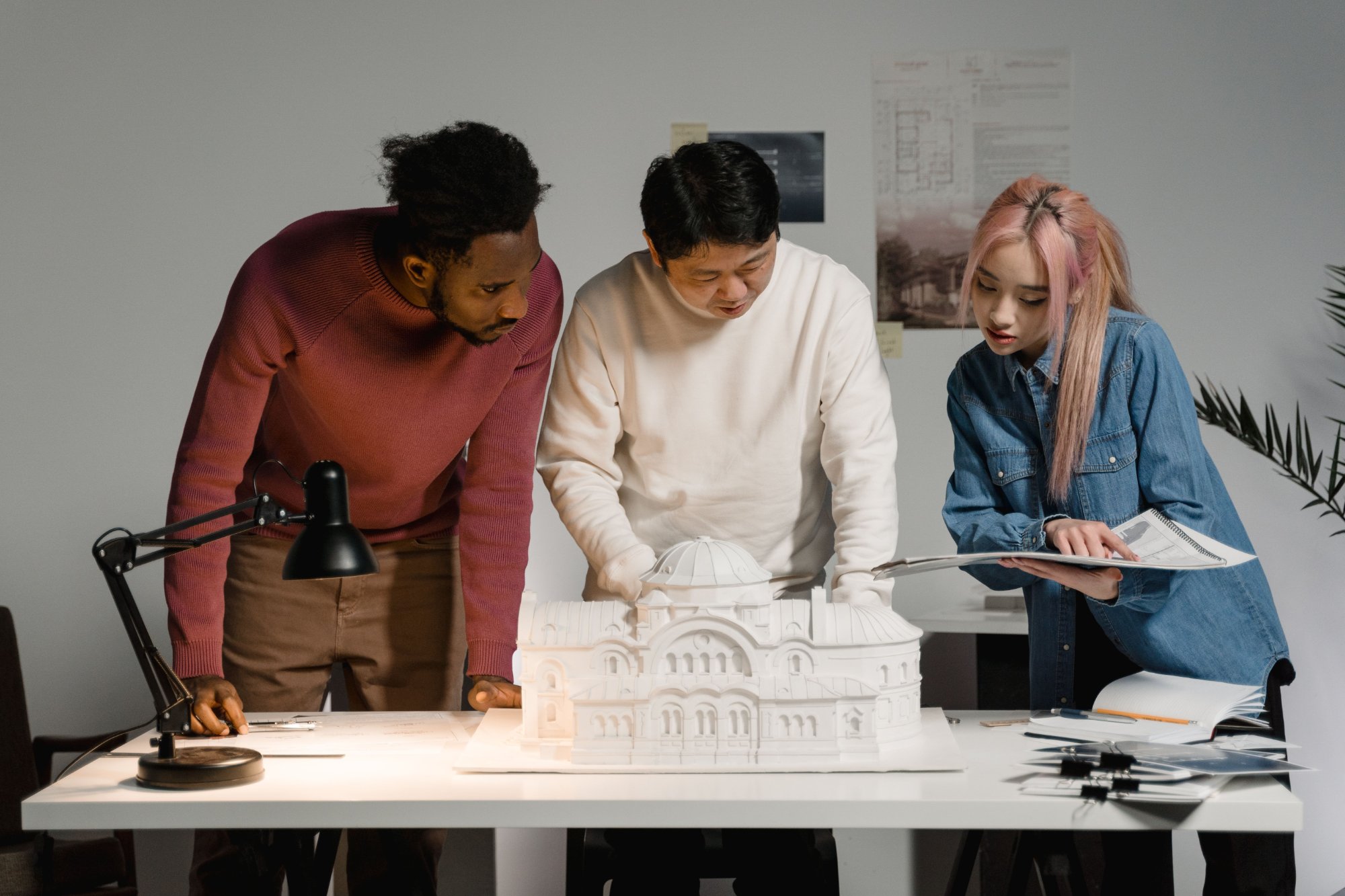 Three architects review a detailed architectural building model.